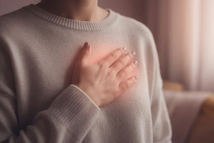 Femme posant délicatement la main sur sa poitrine dans une lumière douce, illustrant l'attention portée aux signaux du corps
