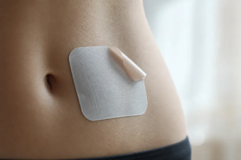 Close-up éditoriale d'un patch minceur adhésif appliqué sur la peau de l'abdomen, photographié dans un style clinique et inve